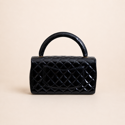 Authentic vintage Chanel Kelly Top Handle handbag in black quilted leather with 24K gold hardware